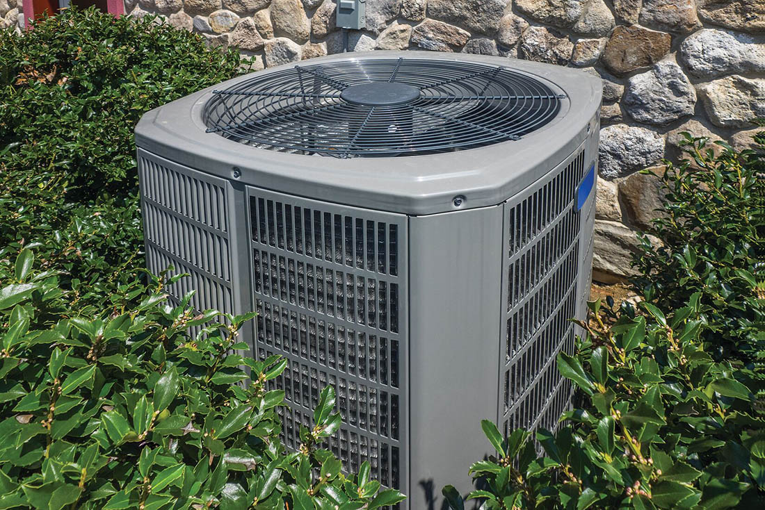 Heat pump on side of house surrounded by landscaping