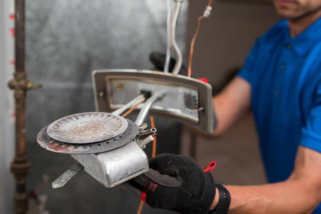 Close-up of a service technician with furnace parts performing a repair service